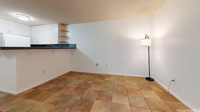 spare room featuring a textured ceiling and light tile patterned flooring