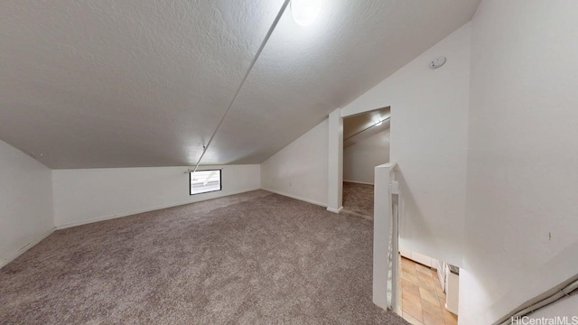 bonus room featuring vaulted ceiling, a textured ceiling, and carpet flooring