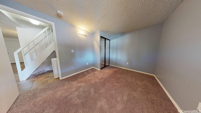 additional living space with carpet flooring, stairs, a textured ceiling, and baseboards