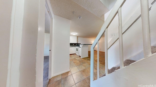 corridor featuring light tile patterned flooring and a textured ceiling