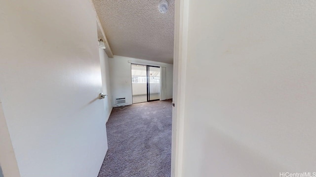 hallway featuring a textured ceiling, carpet, and a wall mounted AC