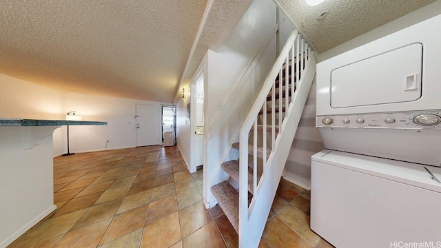 staircase with stacked washing machine and dryer, a textured ceiling, and baseboards