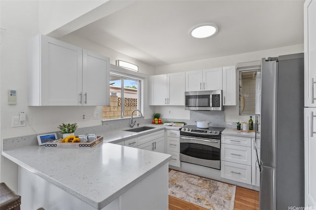 98-533 Kipaepae St Unit 104, Aiea, HI 96701 - kitchen with stainless steel appliances, a sink, a peninsula, white cabinets, and light wood-type flooring