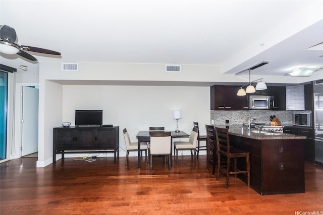 1837 Kalakaua Ave Unit 1102, Honolulu, HI 96815 - kitchen featuring a sink, stainless steel microwave, tasteful backsplash, a kitchen breakfast bar, and wood finished floors