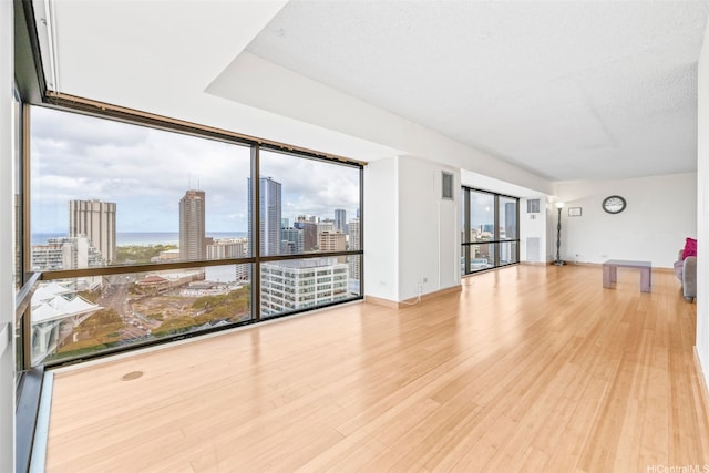 unfurnished living room featuring plenty of natural light, wood finished floors, and a view of city