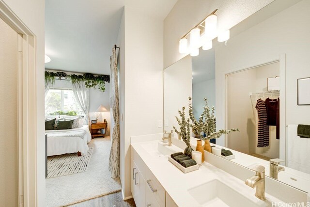 bathroom with ensuite bath, wood finished floors, and double vanity