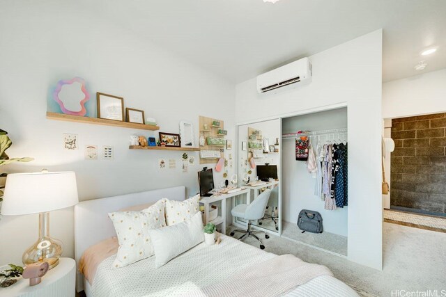 carpeted bedroom with a wall mounted air conditioner, a closet, and a desk