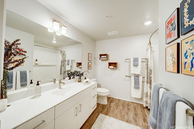 full bath featuring wood finished floors, toilet, vanity, and curtained shower