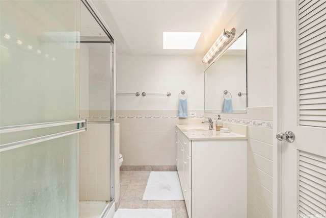 622 Pamaele St, Kailua, HI 96734 - bathroom with a skylight, tile walls, vanity, tile patterned floors, and a wainscoted wall
