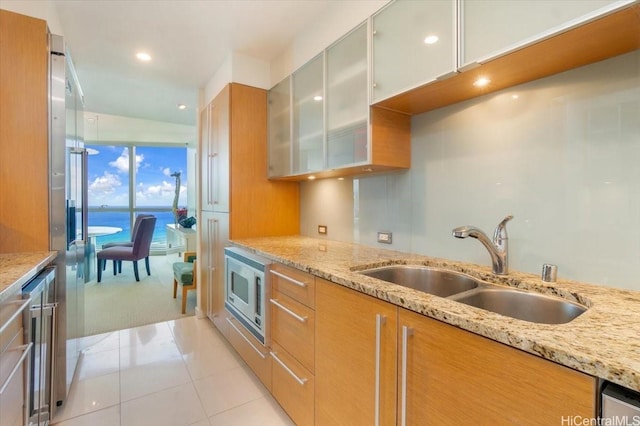 1177 Queen St Unit Ph4608, Honolulu, HI 96814 - kitchen with stainless steel microwave, a sink, light stone countertops, glass insert cabinets, and light tile patterned floors