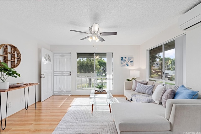 94-820 Lumiauau St Unit G201, Waipahu, HI 96797 - living area with a wall unit AC, healthy amount of natural light, ceiling fan, light wood-style floors, and a textured ceiling