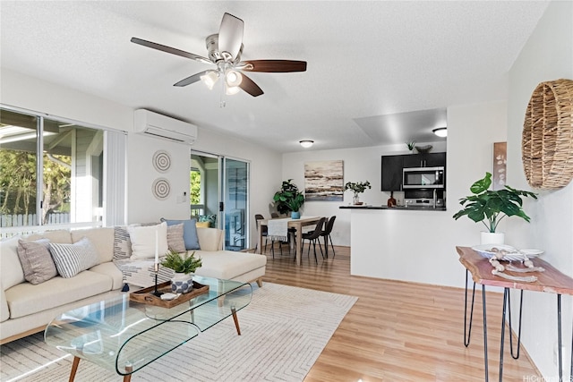 94-820 Lumiauau St Unit G201, Waipahu, HI 96797 - living room featuring an AC wall unit, light wood finished floors, ceiling fan, and a textured ceiling