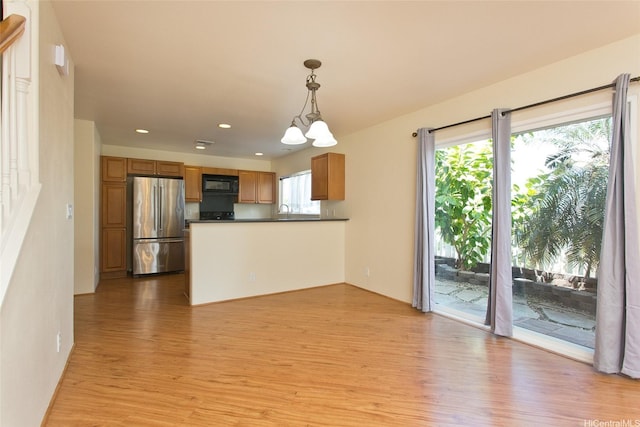 87-2233 Pakeke St, Waianae, HI 96792 - kitchen with freestanding refrigerator, black microwave, light wood-style floors, dark countertops, and a peninsula