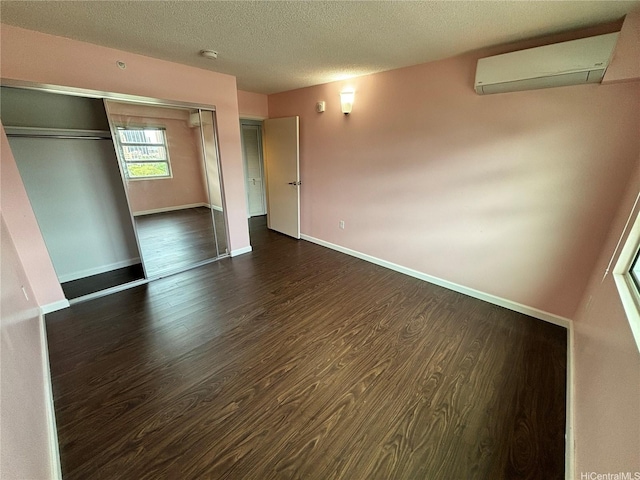 801 S St Unit 1723, Honolulu, HI 96813 - unfurnished bedroom featuring a wall mounted air conditioner, dark wood-style floors, baseboards, a textured ceiling, and a closet