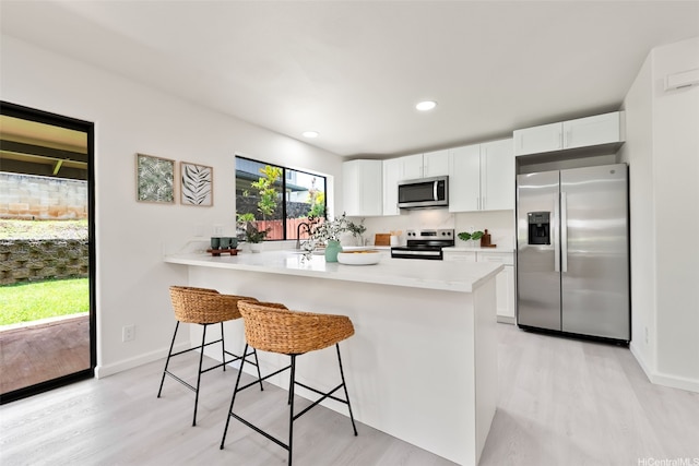 95-1204 Moea St Unit 48, Mililani, HI 96789 - kitchen with appliances with stainless steel finishes, light wood-type flooring, a breakfast bar, white cabinets, and recessed lighting