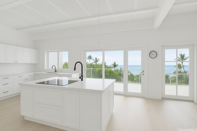 51-470 Lihimauna Rd, Kaaawa, HI 96730 - kitchen with black electric cooktop, beam ceiling, light countertops, light wood finished floors, and a sink