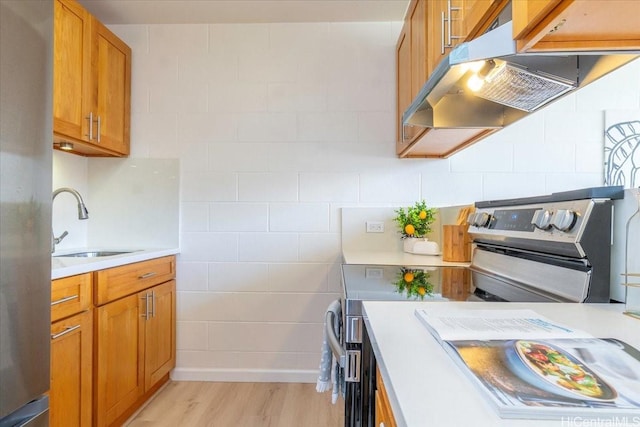 94-327 Hokuahiahi St Unit 325, Mililani, HI 96789 - kitchen with under cabinet range hood, stainless steel electric range oven, light wood finished floors, light countertops, and brown cabinetry