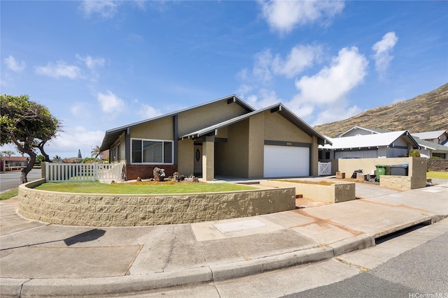 7549 Puumahoe Pl, Honolulu, HI 96825 - view of front facade featuring fence, an attached garage, concrete driveway, stucco siding, and a mountain view