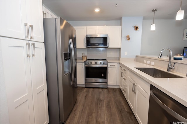 kitchen with appliances with stainless steel finishes, a sink, dark wood-style flooring, white cabinetry, and light countertops