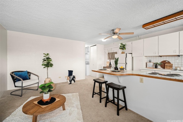 1670 Kalakaua Ave Unit 803, Honolulu, HI 96826 - kitchen with white appliances, light carpet, white cabinets, a peninsula, and a kitchen breakfast bar