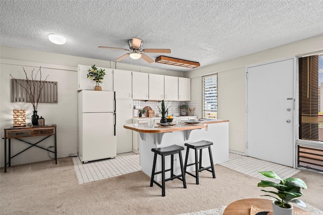 1670 Kalakaua Ave Unit 803, Honolulu, HI 96826 - kitchen with freestanding refrigerator, light countertops, light colored carpet, ceiling fan, and a kitchen bar