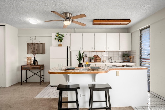 1670 Kalakaua Ave Unit 803, Honolulu, HI 96826 - kitchen with freestanding refrigerator, white cabinetry, ceiling fan, a sink, and a breakfast bar