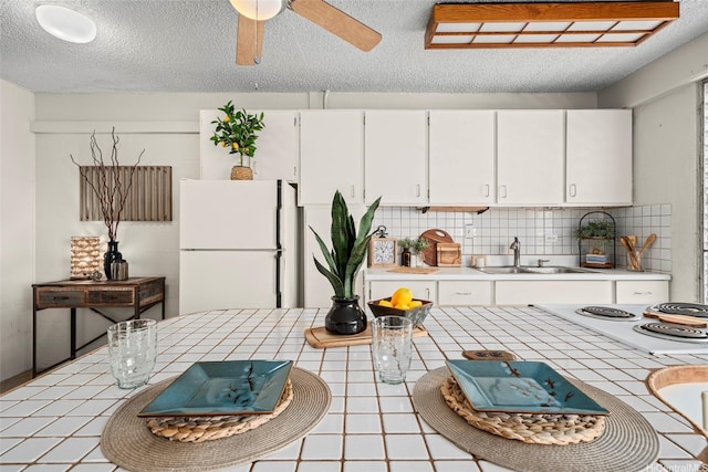 1670 Kalakaua Ave Unit 803, Honolulu, HI 96826 - kitchen featuring a sink, freestanding refrigerator, tile countertops, white cabinetry, and a textured ceiling