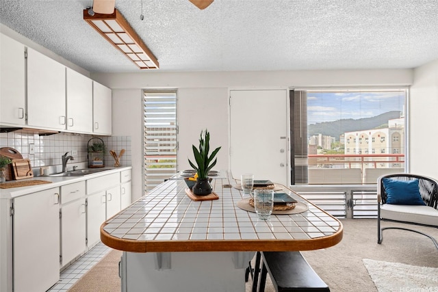 1670 Kalakaua Ave Unit 803, Honolulu, HI 96826 - kitchen featuring tile counters, a sink, a textured ceiling, backsplash, and a kitchen island