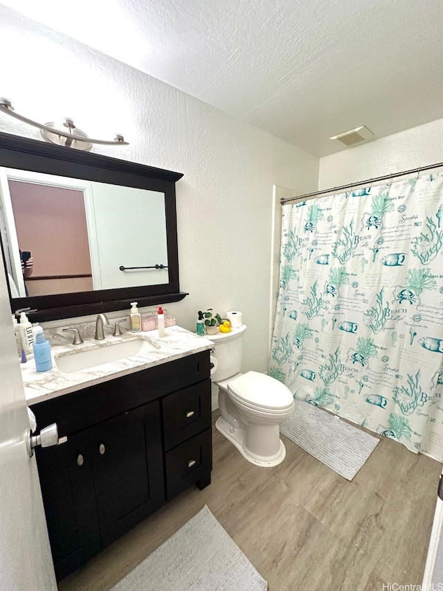 1023 Kapahulu Ave Unit 1, Honolulu, HI 96816 - full bath featuring a textured wall, wood finished floors, toilet, a textured ceiling, and vanity