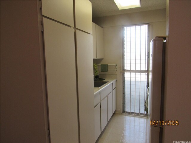 1670 Kalakaua Ave Unit 603, Honolulu, HI 96826 - kitchen with refrigerator, light countertops, light tile patterned floors, and white cabinets