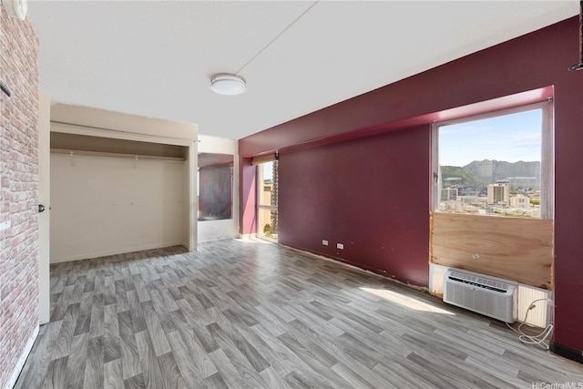 430 Keoniana St Unit 1007, Honolulu, HI 96815 - unfurnished bedroom with wood finished floors, a wall mounted air conditioner, a mountain view, and a closet