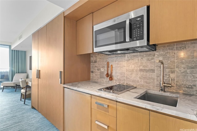 383 Kalaimoku St Unit 1112, Honolulu, HI 96815 - kitchen with stainless steel microwave, a sink, black electric stovetop, light stone counters, and decorative backsplash
