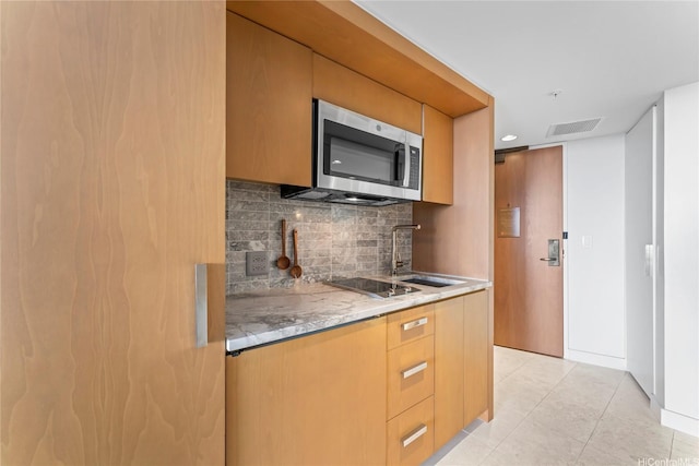 383 Kalaimoku St Unit 1112, Honolulu, HI 96815 - kitchen with stainless steel microwave, a sink, tasteful backsplash, black electric stovetop, and light tile patterned flooring