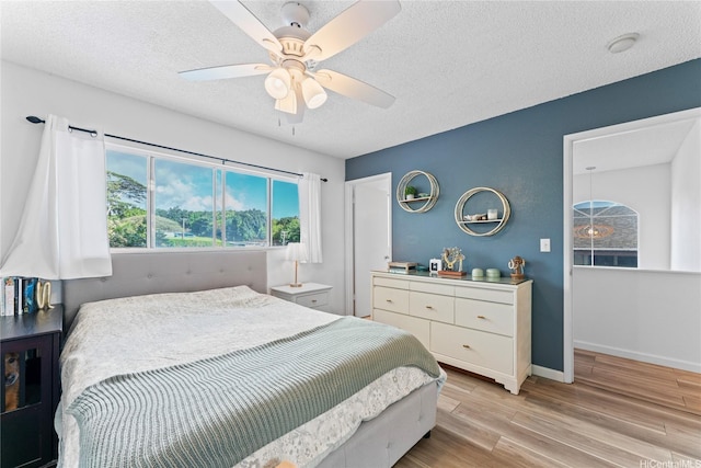 2290 Akepa St, Pearl City, HI 96782 - bedroom with light wood-style flooring, a textured ceiling, a ceiling fan, and baseboards