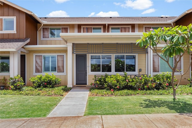 94-1188 Kalahikiola Dr Unit 1004, Waipahu, HI 96797 - view of exterior entry with a yard, a shingled roof, and board and batten siding