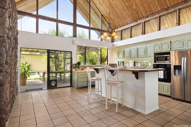 337 Wanaao Rd, Kailua, HI 96734 - kitchen featuring appliances with stainless steel finishes, light tile patterned flooring, high vaulted ceiling, a kitchen bar, and a chandelier