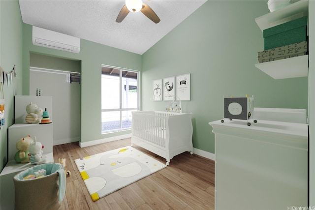 91-127 Puaina Pl, Ewa Beach, HI 96706 - bedroom featuring an AC wall unit, vaulted ceiling, wood finished floors, baseboards, and a ceiling fan