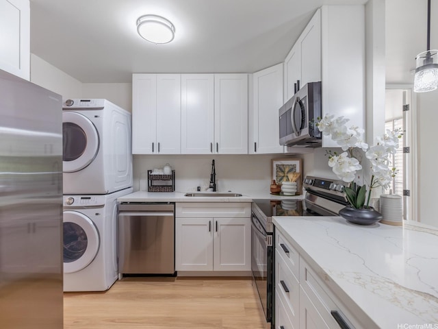 95-65 Waikalani Dr Unit F302, Mililani, HI 96789 - kitchen with stainless steel appliances, a sink, estacked washer and dryer, white cabinetry, and light stone counters