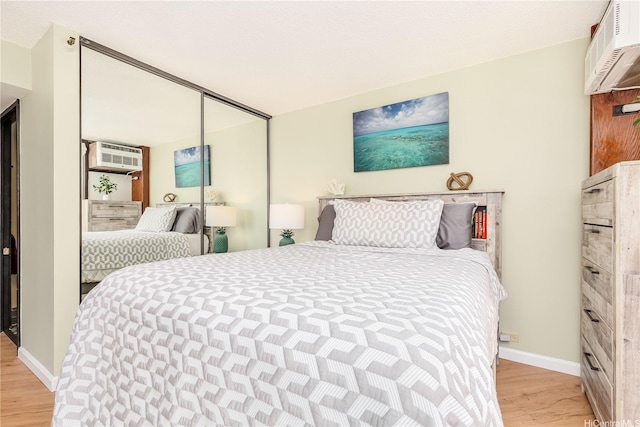 60 N Beretania St Unit 3308, Honolulu, HI 96817 - bedroom with light wood-type flooring, baseboards, a wall mounted air conditioner, and a closet