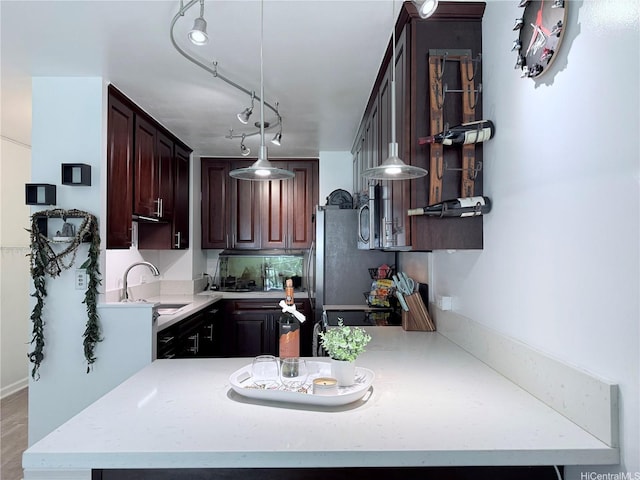 3161 Ala Ilima St Unit 206, Honolulu, HI 96818 - kitchen featuring light countertops, a peninsula, hanging light fixtures, and dark brown cabinetry