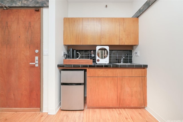 1188 Bishop St Unit 910, Honolulu, HI 96813 - kitchen featuring light wood-style flooring, decorative backsplash, freestanding refrigerator, and tile counters