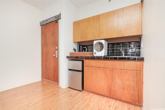 1188 Bishop St Unit 910, Honolulu, HI 96813 - kitchen with freestanding refrigerator, light wood-type flooring, backsplash, and tile counters