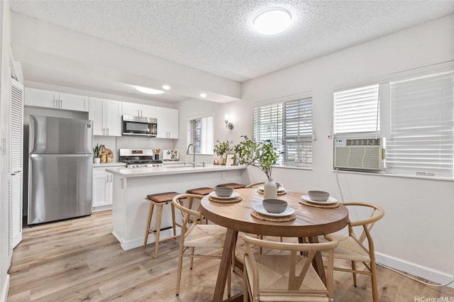 91-1050 Makaaloa St Unit 11E, Ewa Beach, HI 96706 - dining area featuring a textured ceiling, light wood-style flooring, baseboards, and cooling unit