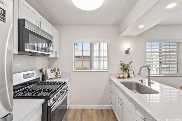 91-1050 Makaaloa St Unit 11E, Ewa Beach, HI 96706 - kitchen with appliances with stainless steel finishes, a sink, light wood finished floors, baseboards, and light stone counters