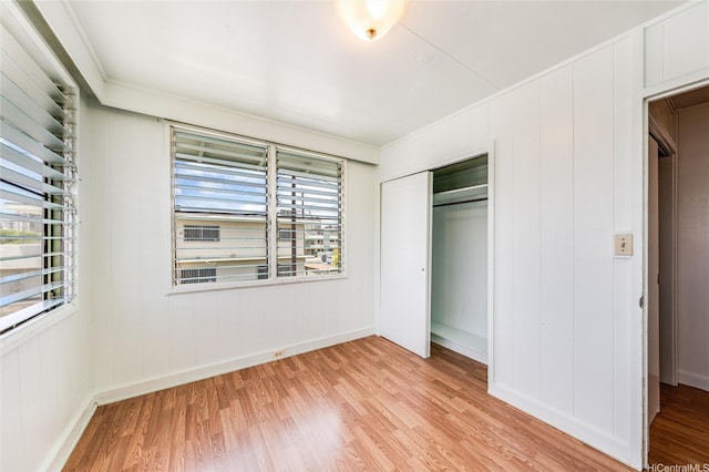 713 Menehune Ln, Honolulu, HI 96826 - unfurnished bedroom featuring light wood finished floors, a closet, crown molding, baseboards, and a decorative wall