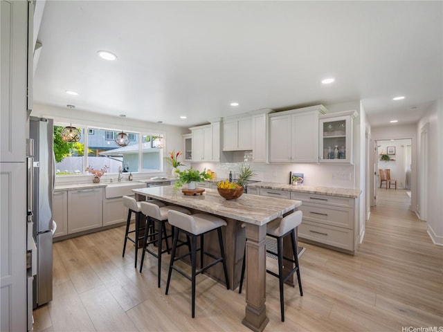 6173 Summer St, Honolulu, HI 96821 - kitchen with freestanding refrigerator, a kitchen bar, light wood-type flooring, light stone counters, and recessed lighting