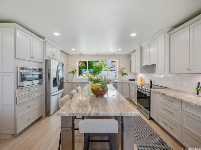 6173 Summer St, Honolulu, HI 96821 - kitchen with appliances with stainless steel finishes, a kitchen bar, light wood-type flooring, tasteful backsplash, and light stone counters