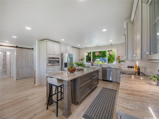 6173 Summer St, Honolulu, HI 96821 - kitchen with stainless steel appliances, a breakfast bar area, a barn door, tasteful backsplash, and light wood-style flooring