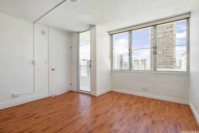 1515 Ward Ave Unit 304, Honolulu, HI 96822 - spare room with wood finished floors, a textured ceiling, baseboards, and healthy amount of natural light