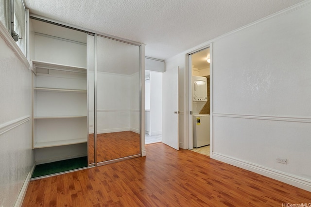 1515 Ward Ave Unit 304, Honolulu, HI 96822 - unfurnished bedroom featuring stacked washer / dryer, wood finished floors, a textured ceiling, baseboards, and a closet